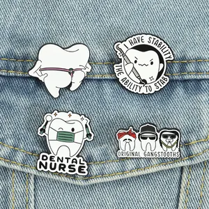 Close-up of four quirky cartoon tooth enamel pins displayed on blue denim fabric