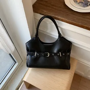 Detailed view of stylish black tote bag with buckle strap on wooden stool