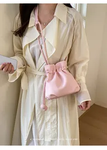 Close-up of a pink minimalist drawstring crossbody bag featuring textured leather