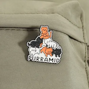 Detailansicht einer 'Purramid' Emaille-Anstecknadel mit süßen gestapelten Katzen auf Stoff