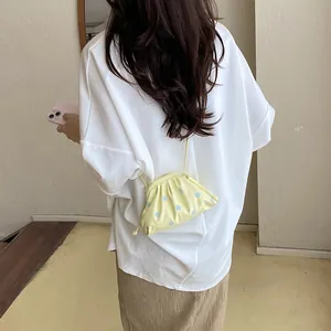 Back view of a chic yellow polka dot crossbody bag worn with a white casual t-shirt.