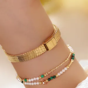 Primer plano detallado de la correa de reloj de malla dorada y pulsera de perlas