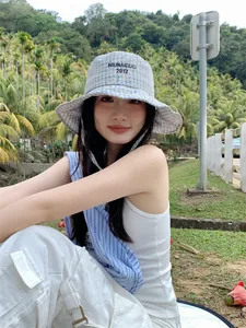 Cappello a secchiello a scacchi blu da donna con ricamo indossato all'aperto