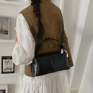 Detailed back view of a woman carrying a stylish vintage black glossy pillow handbag.