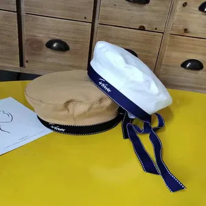 Detail view of stylish berets with bow ribbons and 'forever' embroidery on yellow table.
