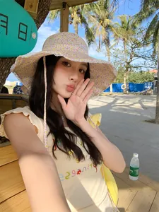 Close-up detail of a floral lace bucket hat worn by a model in a sunny beach setting