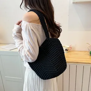 Macro view showing the texture of a minimalist black crochet shoulder bag on a model