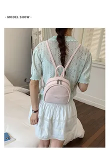 Back view of a sweet pink mini backpack worn by a model in a cozy bedroom setting