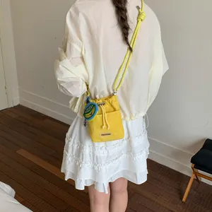 Detailed lifestyle shot of a bright yellow textured crossbody bucket bag with rope strap