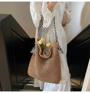 Grand sac bandoulière en paille tressée avec anses rayées dans un cadre de vie