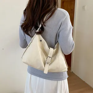 Rear view detail of a chic cream-colored hobo bag worn with a light blue knit sweater