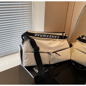 Close-up of a white multi-pocket crossbody gym bag with a branded black strap.