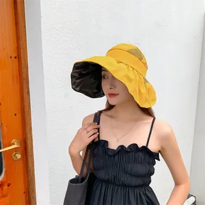 Model showcasing a yellow wide brim UV protection sun hat featuring black vinyl lining detail.