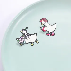 Paar schattige witte ganzen emaille pins met roze hoeden en laarzen die boeken dragen