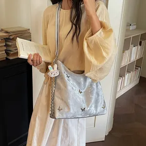 Silver butterfly-patterned large crossbody bag shown on model in a lifestyle setting