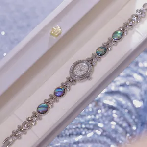 Primer plano de reloj plateado para mujer con pulsera de concha de abulón natural