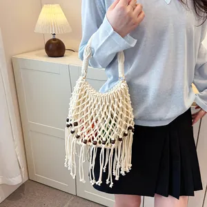 Handmade white macrame woven tote bag with fringe and wooden bead details shown on model.