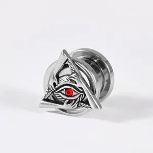 Detail of stainless steel ear gauge featuring a triangle evil eye design with red rhinestone.
