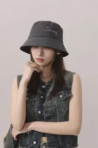 Vista detallada del sombrero de pescador en algodón gris oscuro con bordado en el modelo.
