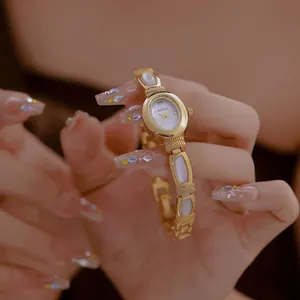 Primer plano del reloj de pulsera dorado Bee Sister con esfera de nácar blanco.