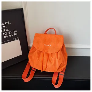 Detail of a vibrant orange checkered casual mini backpack for women on a black surface.