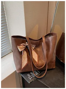 Detail view of large brown tote bag with geometric embossing and decorative scarf