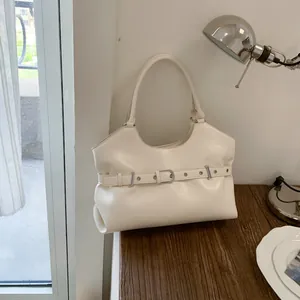 Detailed view of cream-colored faux leather shoulder bag with decorative belt buckle