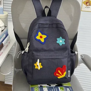 Detailed view of a cute grey school backpack featuring colorful embroidered flower patches