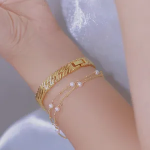 Primer plano de un reloj de cadena dorado vintage y una pulsera de perlas en la muñeca