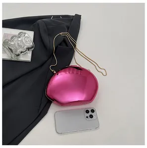 Dettaglio di una borsa da sera a conchiglia a specchio rosa con catena e scala di misura