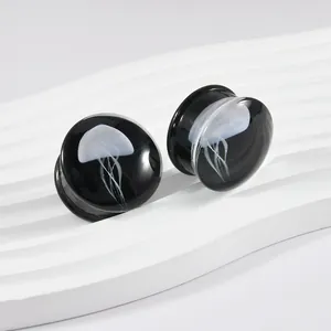 Detailansicht schwarzer Glas-Ohr Plugs mit zarten weißen Quallenmustern im Inneren.
