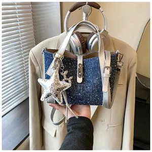 Detailed view of stylish denim bucket bag featuring silver star charm and leather trim