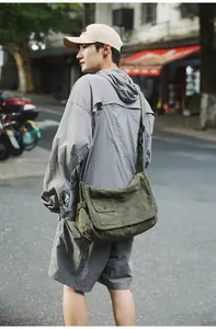 Model carrying large capacity army green canvas messenger bag in urban setting
