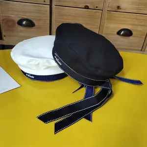 Detail view of black and white berets with long ribbons and 'forever' embroidery.