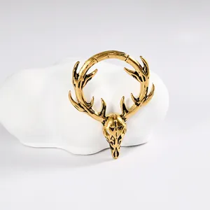 Détail d'une boucle d'oreille en acier inoxydable doré tête de cerf sur support blanc.