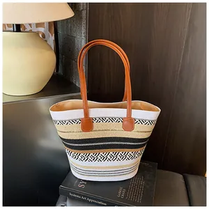 Nahaufnahme einer großen geflochtenen Strohtasche mit braunen Lederriemen für den Strand
