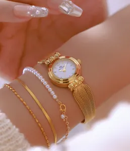 Primer plano de elegante reloj dorado con pulseras de perlas y oro en la muñeca