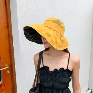 Woman wearing a large brim yellow sun hat with black vinyl lining for UV protection