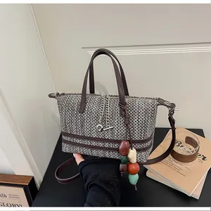 Detail view of a woven bucket bag featuring decorative beads and a silver chain strap.