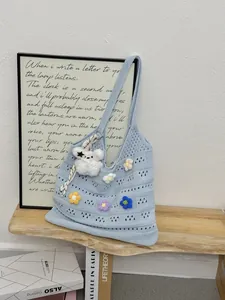 Handgewebte blaue Strick-Einkaufstasche mit bunten Blumenakzenten auf Holzregal