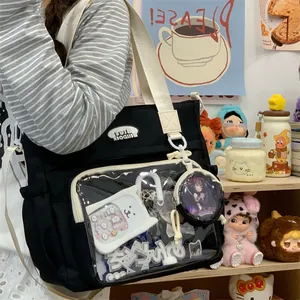 Detailed view of black canvas ita bag with transparent window and cute accessories.