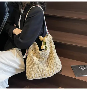 Détail d'un sac cabas en paille tressée crème avec bandoulière à motifs