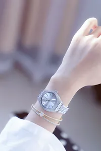 Detalle del reloj plateado para mujer con pedrería y pulseras a juego.