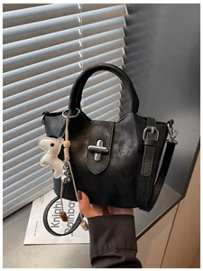Détail d'un sac seau noir chic avec fermoir rotatif argenté et breloque petit chien.