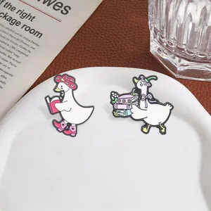 Set van twee schattige cartoon lezende gans emaille spelden met roze hoed en boekdetails