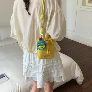 Detailed view of a yellow drawstring bucket bag with a banana patch worn by a model.