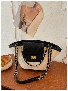 Gros plan d'un sac cabas en paille d'été avec rabat à losanges noirs et chaîne dorée.