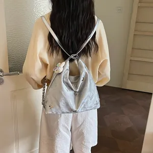 Back view of a silver multifunctional backpack with butterfly charms on a model