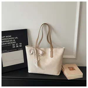 Elegant cream tote bag with geometric embossing and silk scarf detail for commuter style