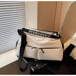 Close-up detail of a white multi-pocket sports crossbody bag with a branded black strap